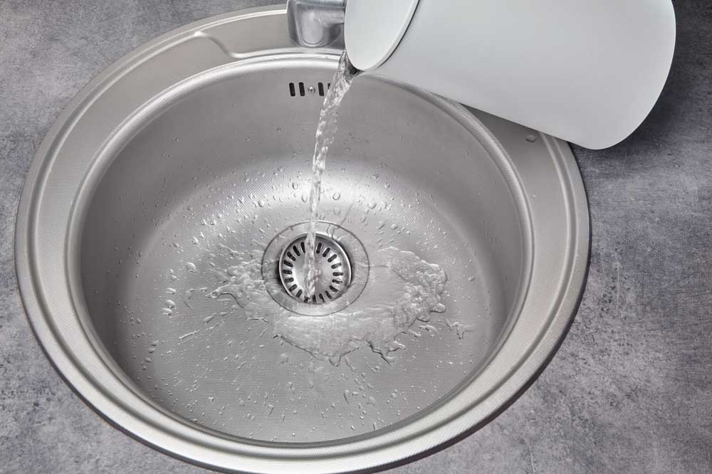 pouring water from kettle into sink