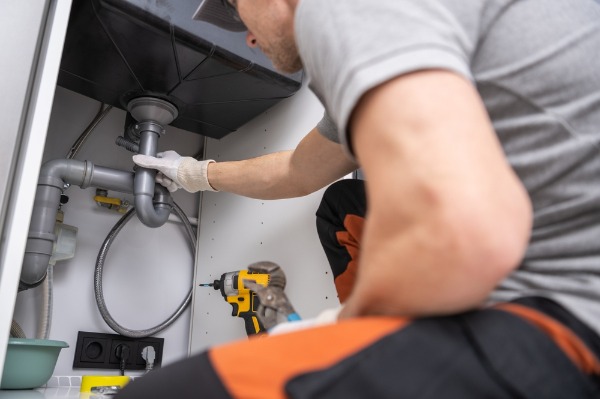 plumber repairing kitchen sink pipes