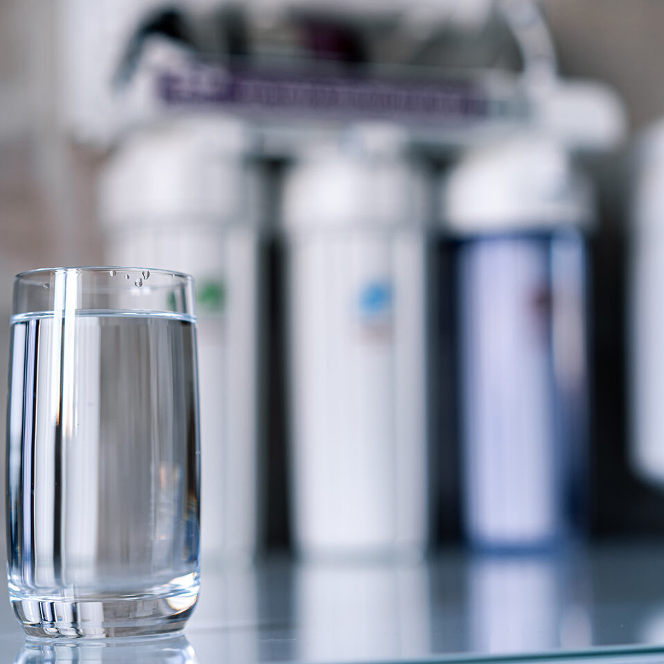 Pure,Water,In,Glass,And,Water,Filters,On,The,Blurred Pure water in glass and water filters on the blurred background. Household filtration system.